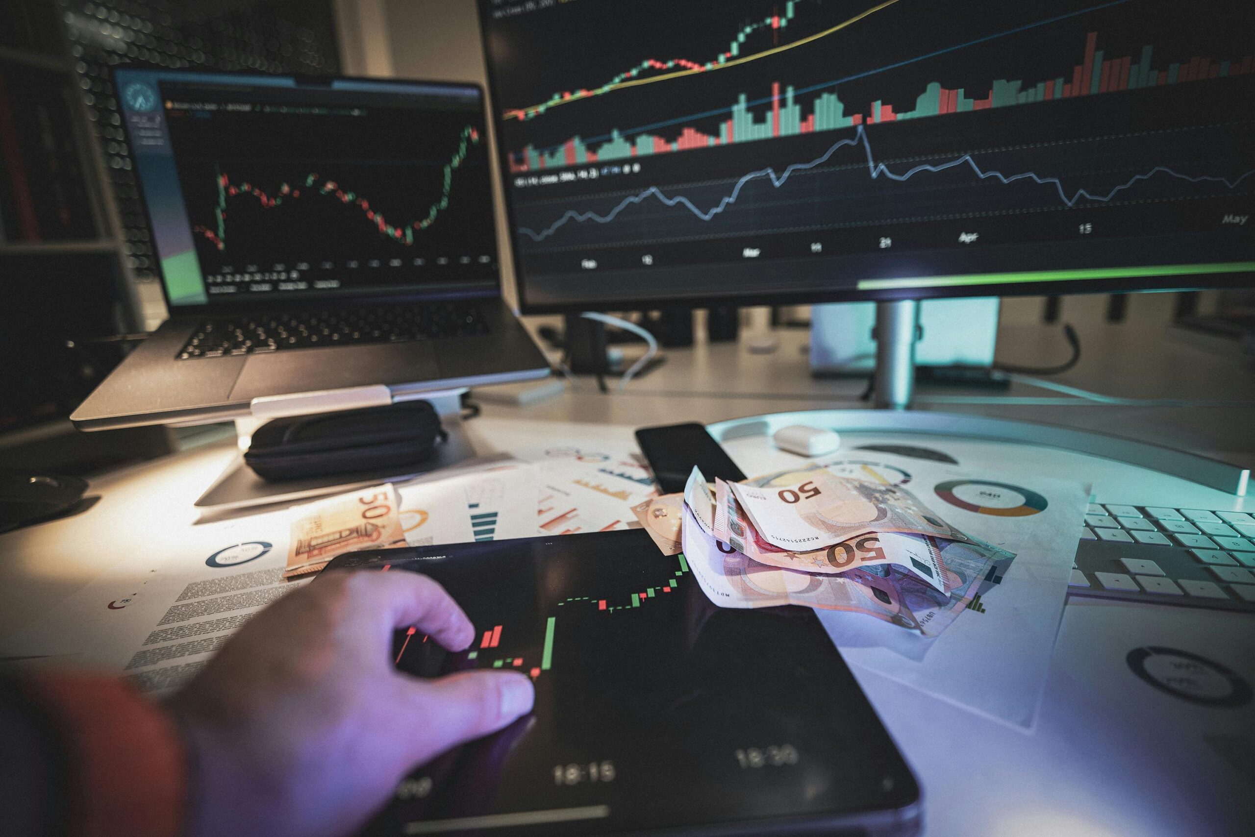 A modern trading desk with screens showing market charts and euro notes, capturing a trading atmosphere.